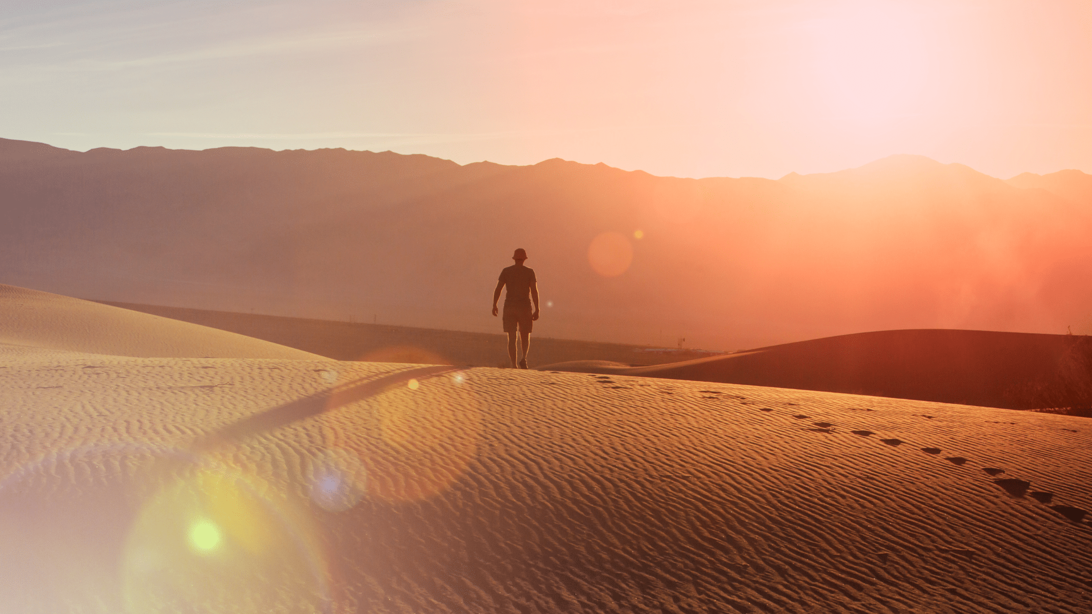 Person walking alone across desert dunes at sunrise, symbolizing a vision quest and spiritual rite of passage