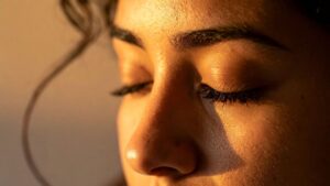 Woman with eyes closed representing sensitivity and spiritual awareness, grounding, and the connection between intuition and trauma