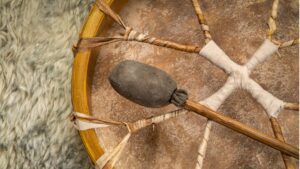 Shamanic drum and beater resting on sheepskin, illustrating hero image what is a shamanic journey and the drum's role as the heartbeat of the earth